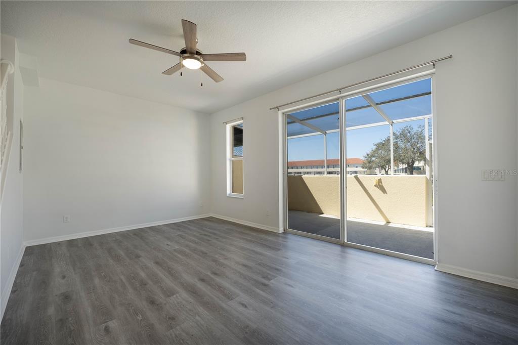 An empty room with gray wood-look flooring, a ceiling fan, and a sliding glass door — 1241 S BEACH CIRCLE, KISSIMMEE, FL