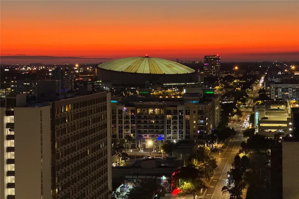 An aerial view of a city skyline at sunset featuring a large domed stadium — 400 CENTRAL AVENUE UNIT 1801, ST PETERSBURG, FL