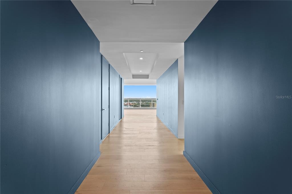A hallway with blue walls and light wood flooring leads to a balcony with views — 400 CENTRAL AVENUE UNIT 1801, ST PETERSBURG, FL