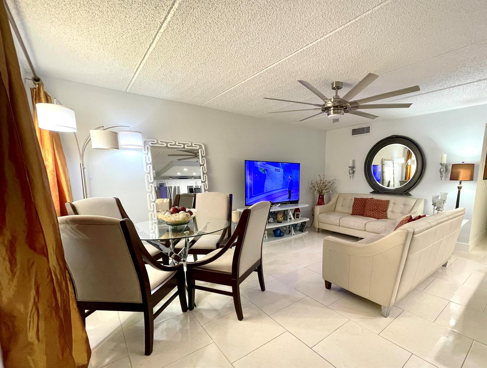 A living and dining room with white tile floors, a ceiling fan, and neutral furniture — 3200 Springdale Boulevard # 107, Palm Springs FL 33461, PALM SPRINGS, FL