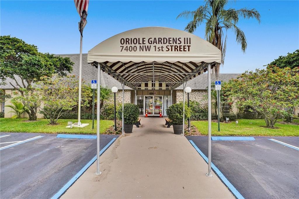 The exterior entrance of a building features a striped awning over a concrete walkway — 201 NW 76th Avenue # 203, Margate FL 33063, MARGATE, FL
