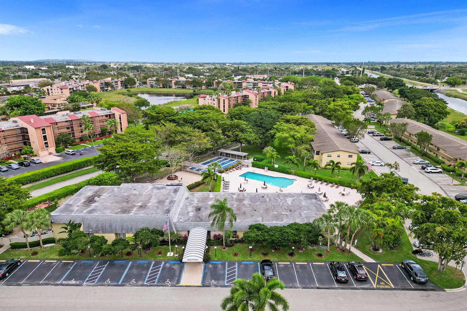 An aerial view shows a community clubhouse with a swimming pool and surrounding apartment buildings — 201 NW 76th Avenue # 203, Margate FL 33063, MARGATE, FL