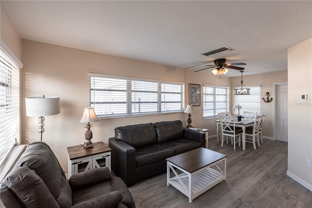 A living and dining area features a leather sofa, recliner, coffee table, and wood flooring — 6020 MIDNIGHT PASS ROAD UNIT 50, SARASOTA, FL