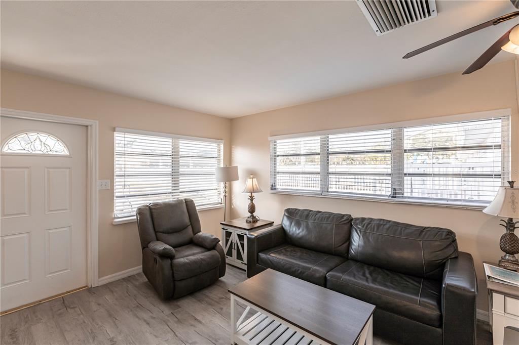 A living room features a dark leather sofa, a matching recliner, and light wood flooring — 6020 MIDNIGHT PASS ROAD UNIT 50, SARASOTA, FL