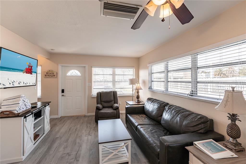 A living room features a dark leather sofa, a recliner, and a white media console — 6020 MIDNIGHT PASS ROAD UNIT 50, SARASOTA, FL