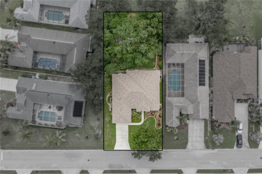 An aerial view shows a single-family house with a driveway and a wooded backyard — 12215 WOODLANDS CIRCLE, DADE CITY, FL