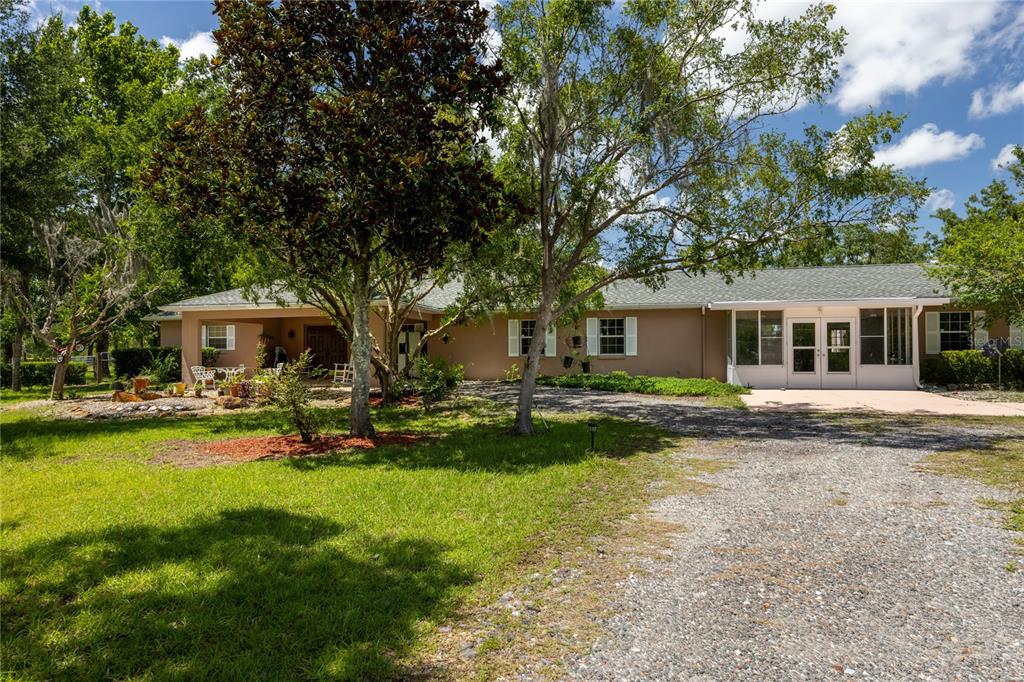 A single-story house with a gravel driveway, a covered patio, and a sunroom — 11751 SE 16TH LANE, MORRISTON, FL