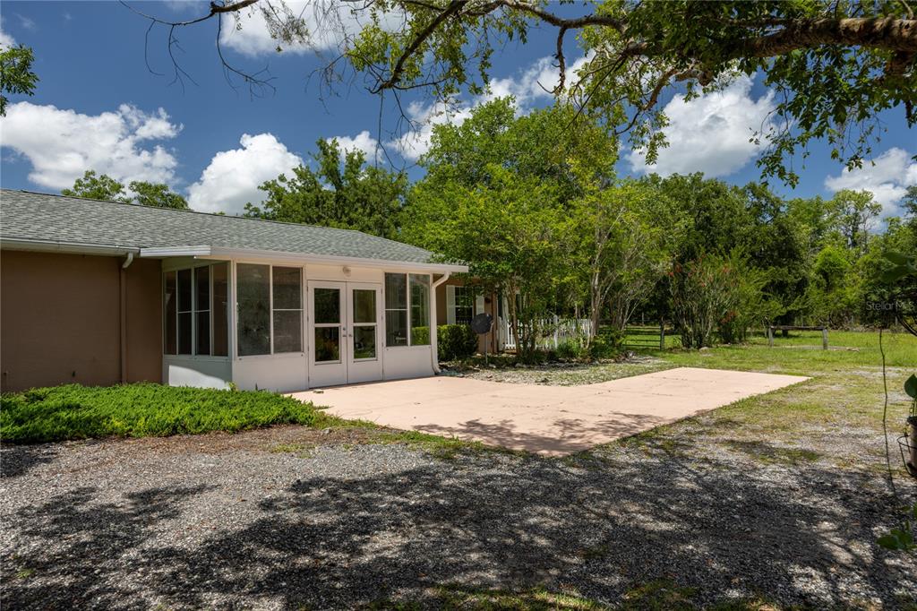 A house exterior features a white-framed sunroom with double doors opening onto a concrete patio — 11751 SE 16TH LANE, MORRISTON, FL