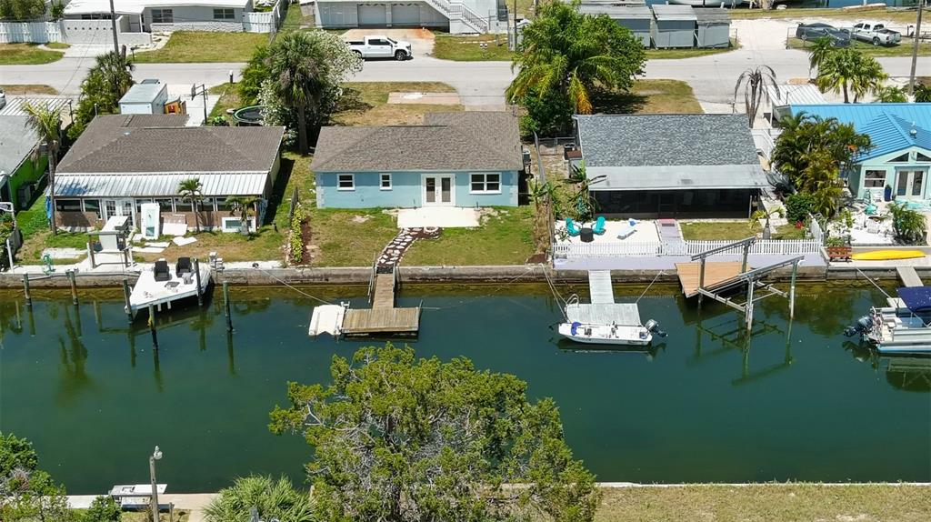 An aerial view shows three waterfront houses along a canal with private docks and boats — 6432 BOATYARD DRIVE, HUDSON, FL