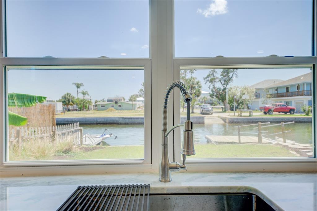 A kitchen sink with a gooseneck faucet overlooks a canal and residential neighborhood — 6432 BOATYARD DRIVE, HUDSON, FL