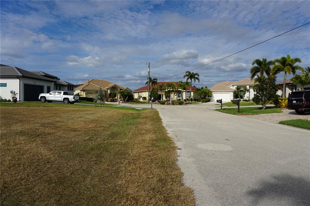 A residential street view showing houses, palm trees, a parked truck, and a grassy lot — 4019 MALTESE COURT, PUNTA GORDA, FL