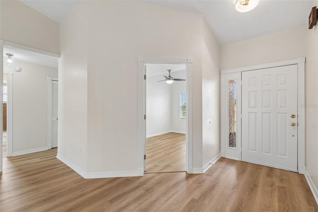An entryway with light wood-look flooring, white walls, and a white front door — 12486 CENTENNIAL STREET, SPRING HILL, FL