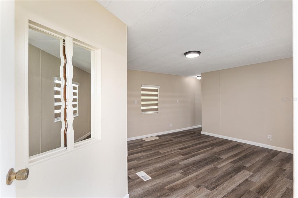An interior view of a room with wood-look flooring, beige walls, and a decorative window — 5910 SW 63RD PLACE ROAD, OCALA, FL