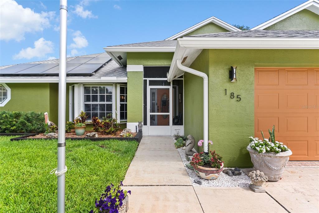 The exterior of a green house features a garage, a front walkway, and solar panels — 185 JOY HAVEN DRIVE, SEBASTIAN, FL