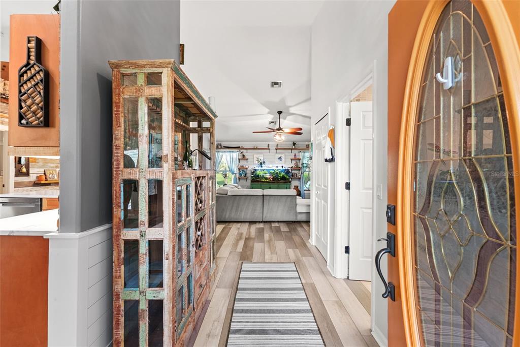 An entryway leads into a living room with wood-look flooring and a rustic display cabinet — 185 JOY HAVEN DRIVE, SEBASTIAN, FL