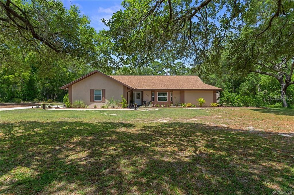 A single-story house with a tan exterior and a brown shingled roof sits on a lawn — 807 W NATIONAL STREET, HERNANDO, FL