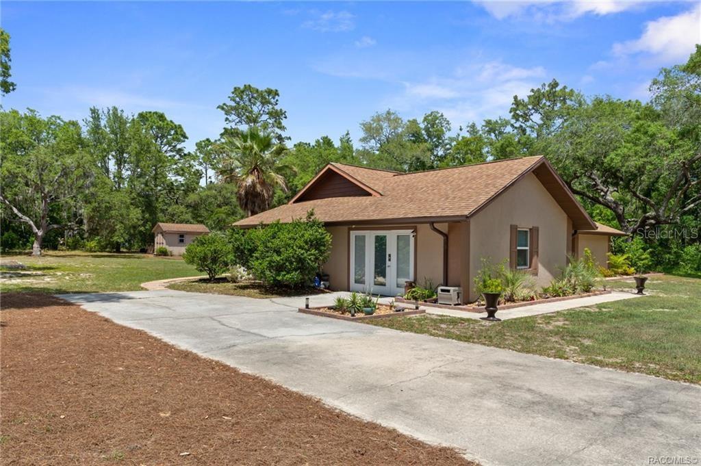 A single-story house with a concrete driveway, brown roof, and surrounding trees — 807 W NATIONAL STREET, HERNANDO, FL