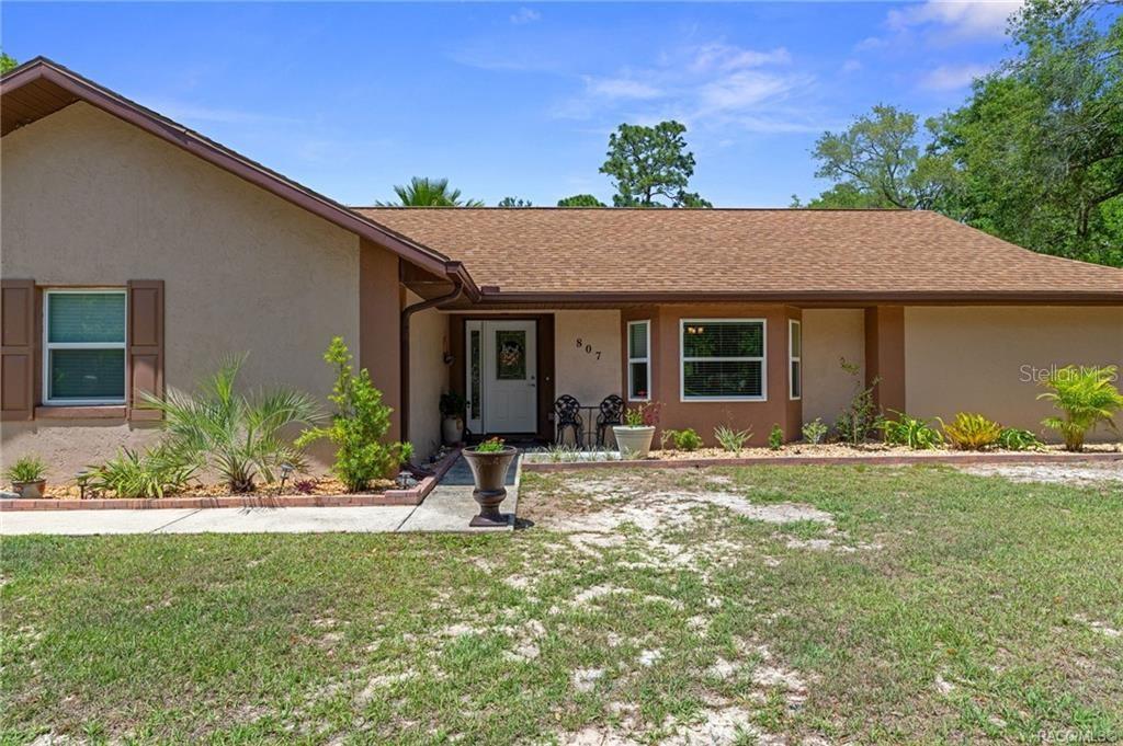 A single-story house with a tan stucco exterior, brown trim, and a shingled roof — 807 W NATIONAL STREET, HERNANDO, FL