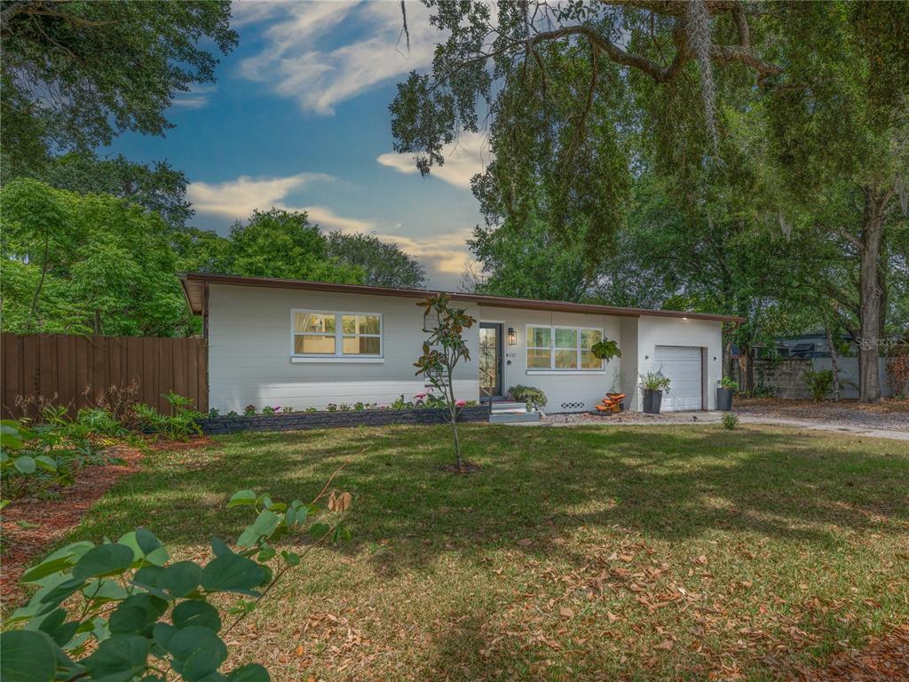 A single-story house with light-colored siding, a small garage, and a front lawn with trees — 2702 S SHINE AVENUE, ORLANDO, FL