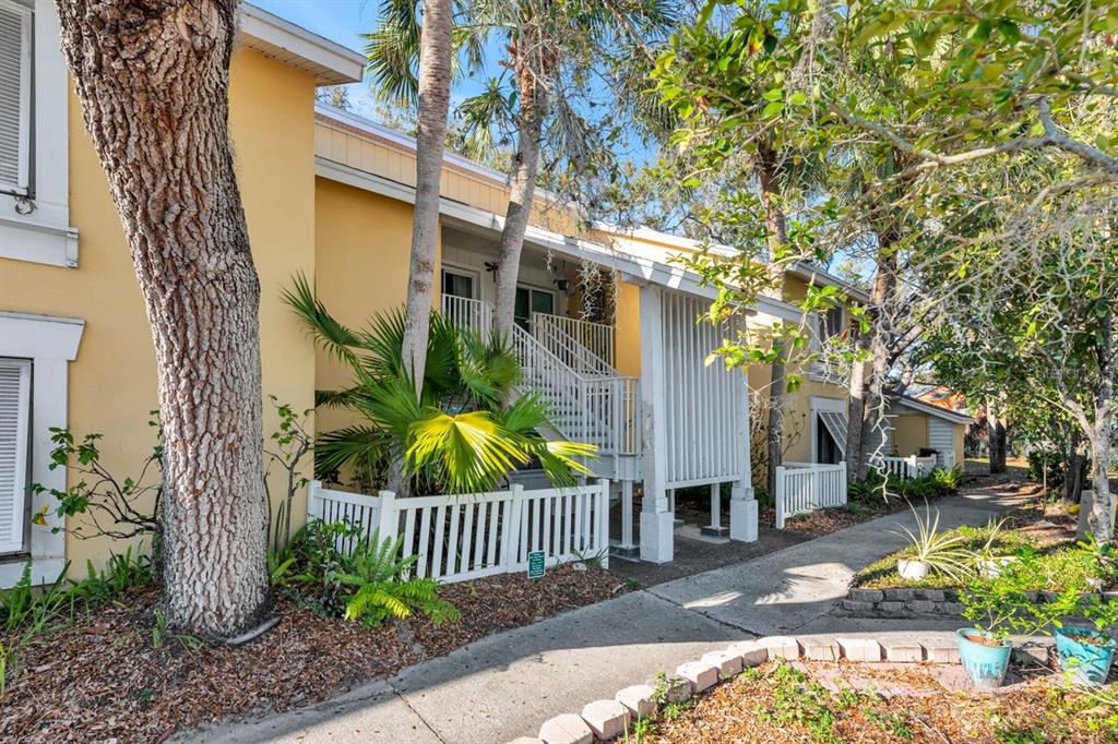 Exterior view of a yellow two-story apartment building with stairs and a white picket fence — 3765 41ST STREET S UNIT K, ST PETERSBURG, FL