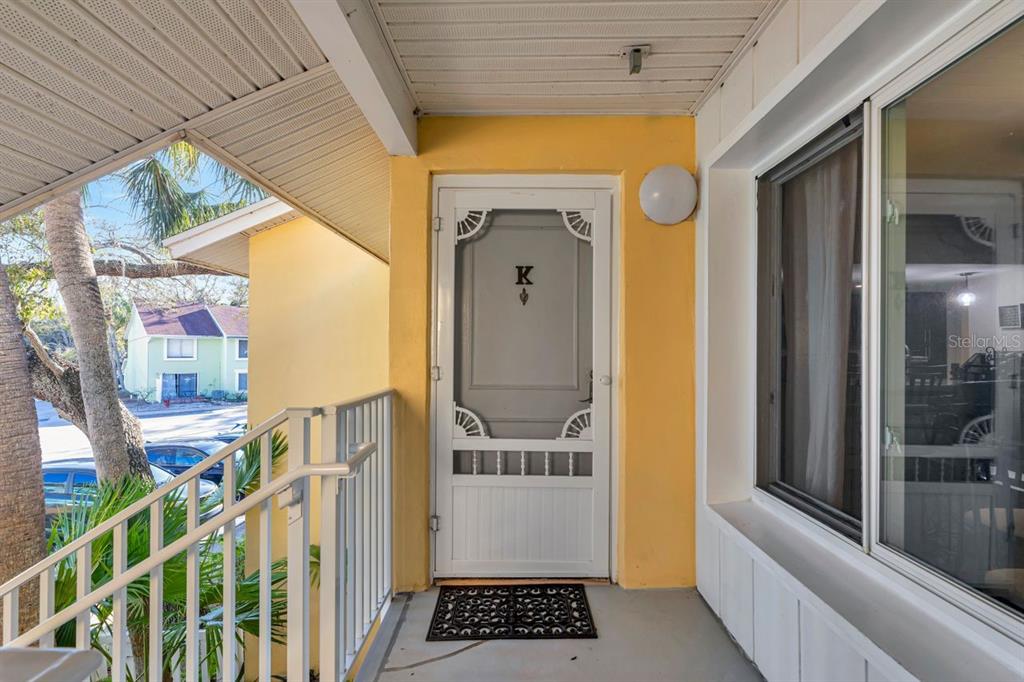 An exterior view of a covered apartment entryway with a yellow wall and screen door — 3765 41ST STREET S UNIT K, ST PETERSBURG, FL
