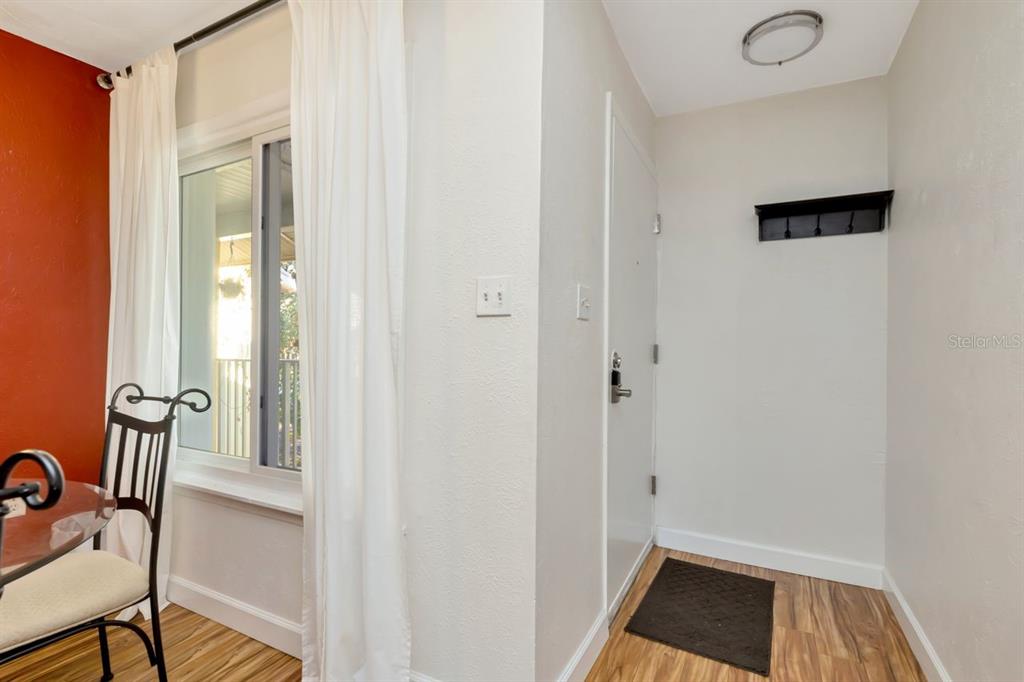 An entryway with wood-look flooring, a white door, and a black wall-mounted coat rack — 3765 41ST STREET S UNIT K, ST PETERSBURG, FL