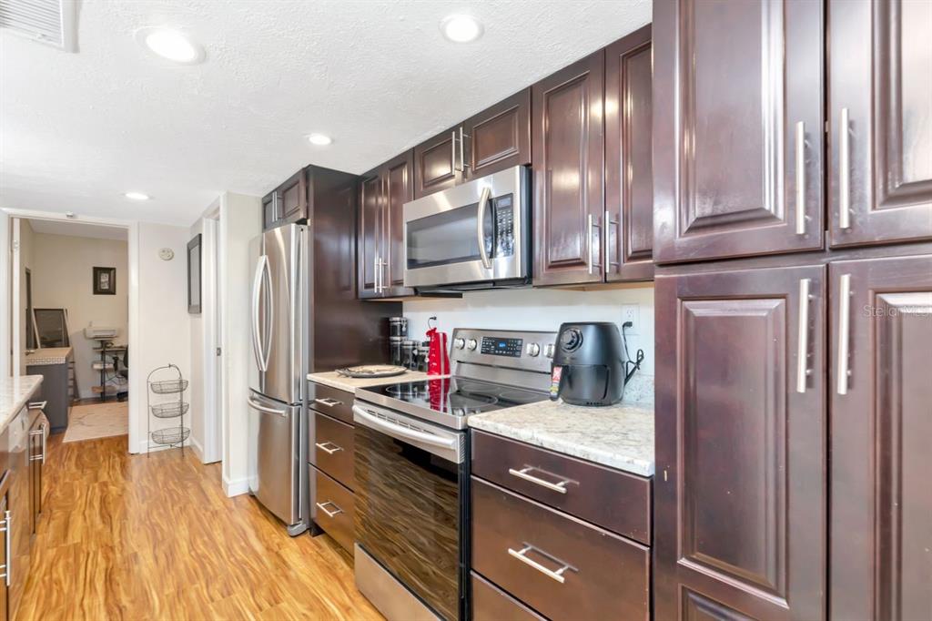 A kitchen features dark wood cabinets, stainless steel appliances, and light-colored granite countertops — 3765 41ST STREET S UNIT K, ST PETERSBURG, FL
