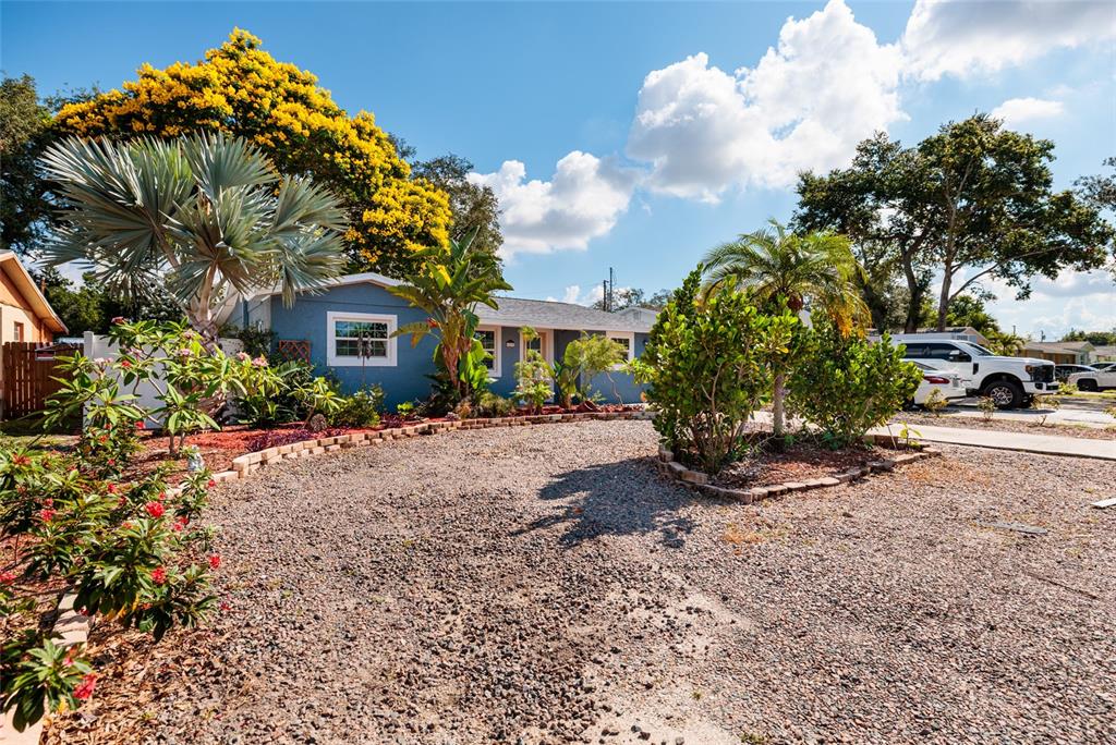 A blue house with a gravel driveway and tropical landscaping under a sunny sky — 6275 51ST AVENUE N, ST PETERSBURG, FL