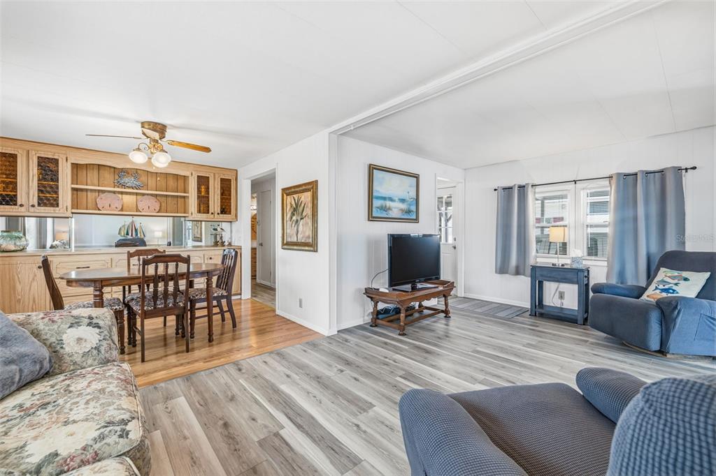A living room and dining area with wood-look flooring, a ceiling fan, and wood cabinetry — 3632 TIKI DRIVE, HOLIDAY, FL