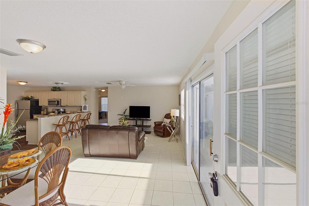 An open-concept living and dining area features tile flooring, a kitchen island, and sliding doors — 2343 PINE RIDGE STREET, THE VILLAGES, FL