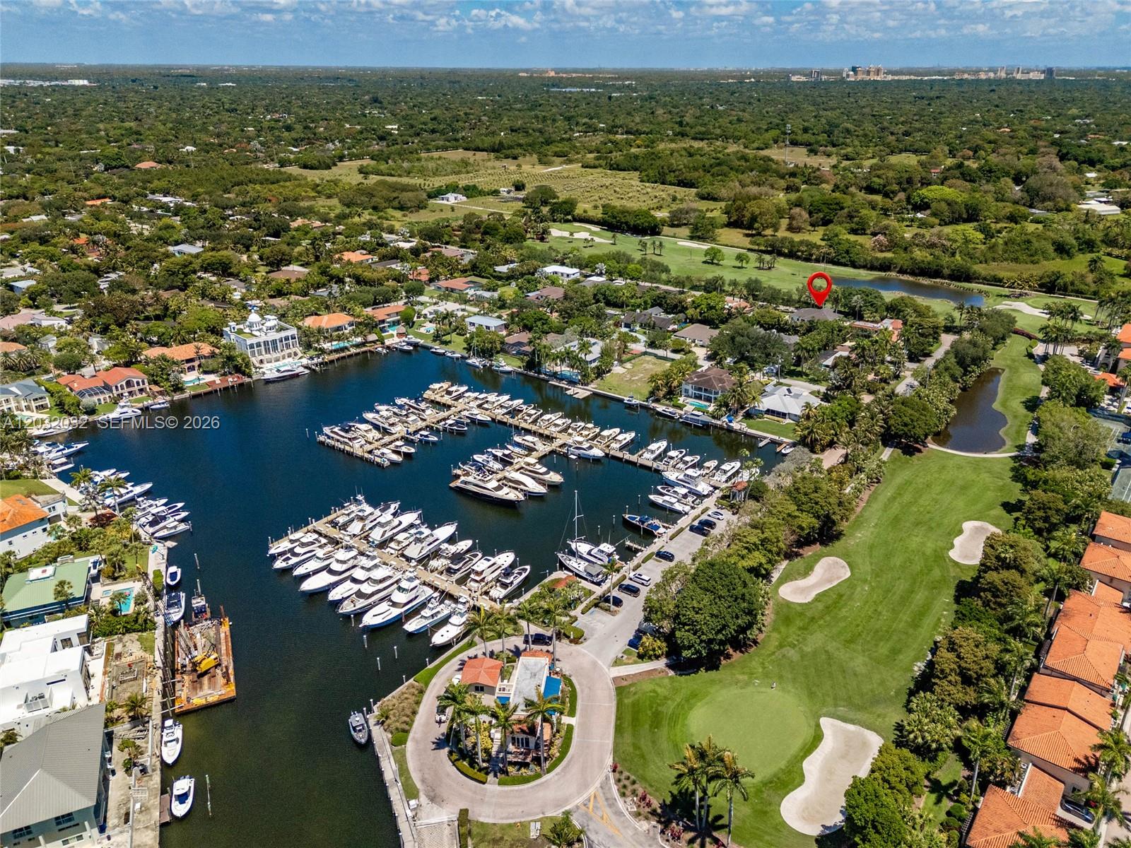 An aerial view shows a marina with numerous docked boats adjacent to a golf course — 6220 SW 144th St, Coral Gables FL 33158, CORAL GABLES, FL
