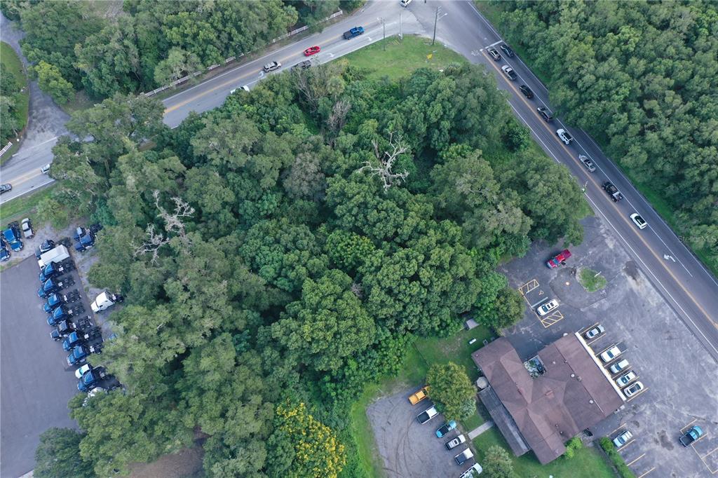 An aerial view shows a wooded lot situated between two roads and adjacent buildings — 24439 SORRENTO AVENUE, SORRENTO, FL