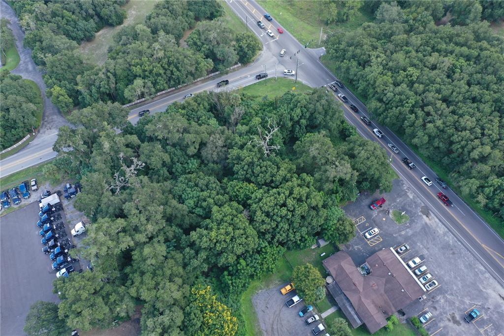 An aerial view shows a wooded lot situated between a parking area and two intersecting roads — 24439 SORRENTO AVENUE, SORRENTO, FL