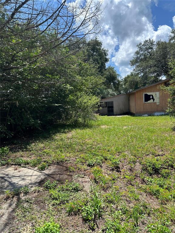 A small, wood-sided house sits in a grassy yard with a large satellite dish — 1968 SE 161ST TERRACE, OCKLAWAHA, FL