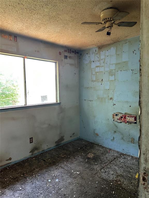 A dilapidated bedroom with a ceiling fan, stained walls, and debris-covered flooring — 1968 SE 161ST TERRACE, OCKLAWAHA, FL