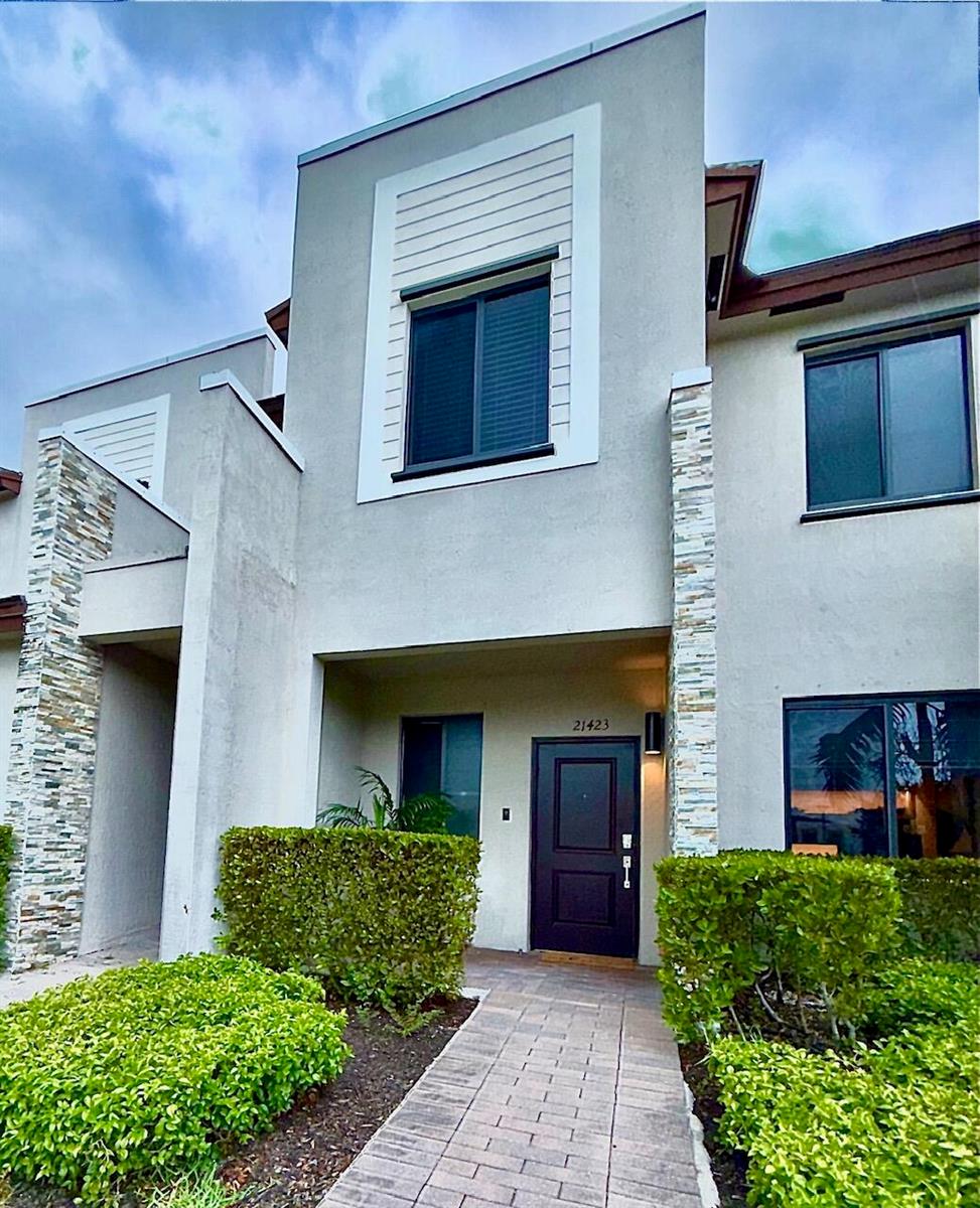 The exterior of a two-story townhouse features a stone-accented facade, a paved walkway, and landscaping — 21423 NE 2nd Place, Miami FL 33179, MIAMI, FL