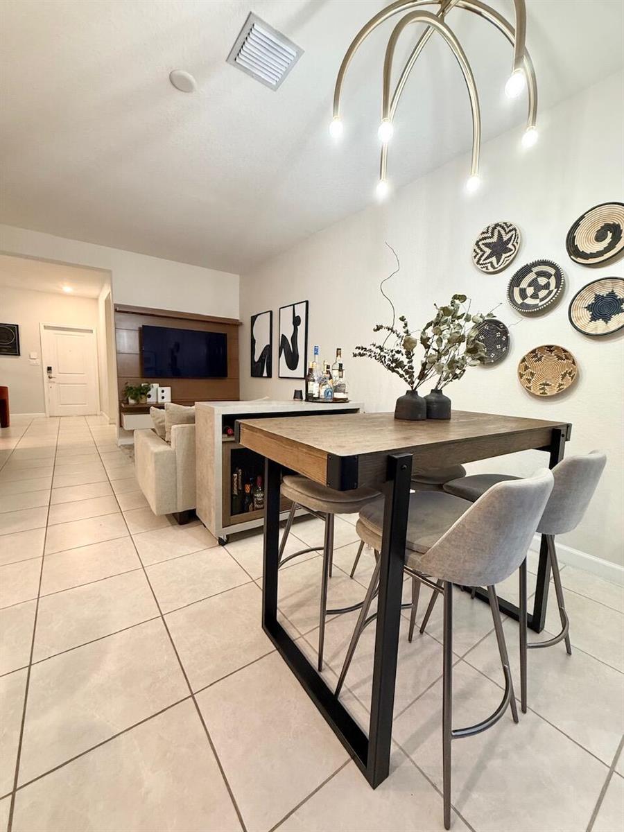 A dining area features a wooden table with metal legs and three gray bar stools — 21423 NE 2nd Place, Miami FL 33179, MIAMI, FL