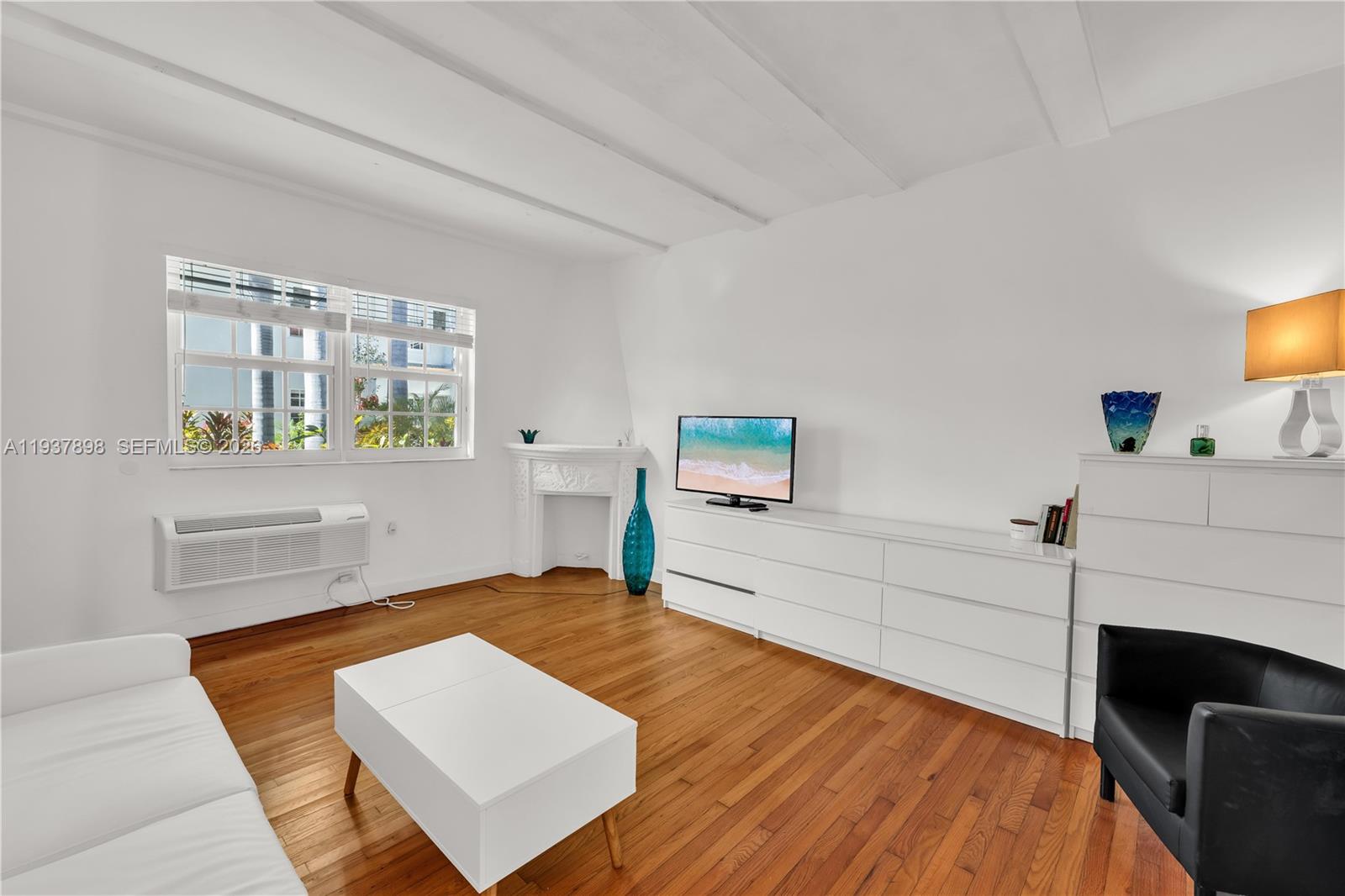 A living room features white walls, hardwood floors, a fireplace, and a white dresser — 439 15th St # 2, Miami Beach FL 33139, MIAMI BEACH, FL