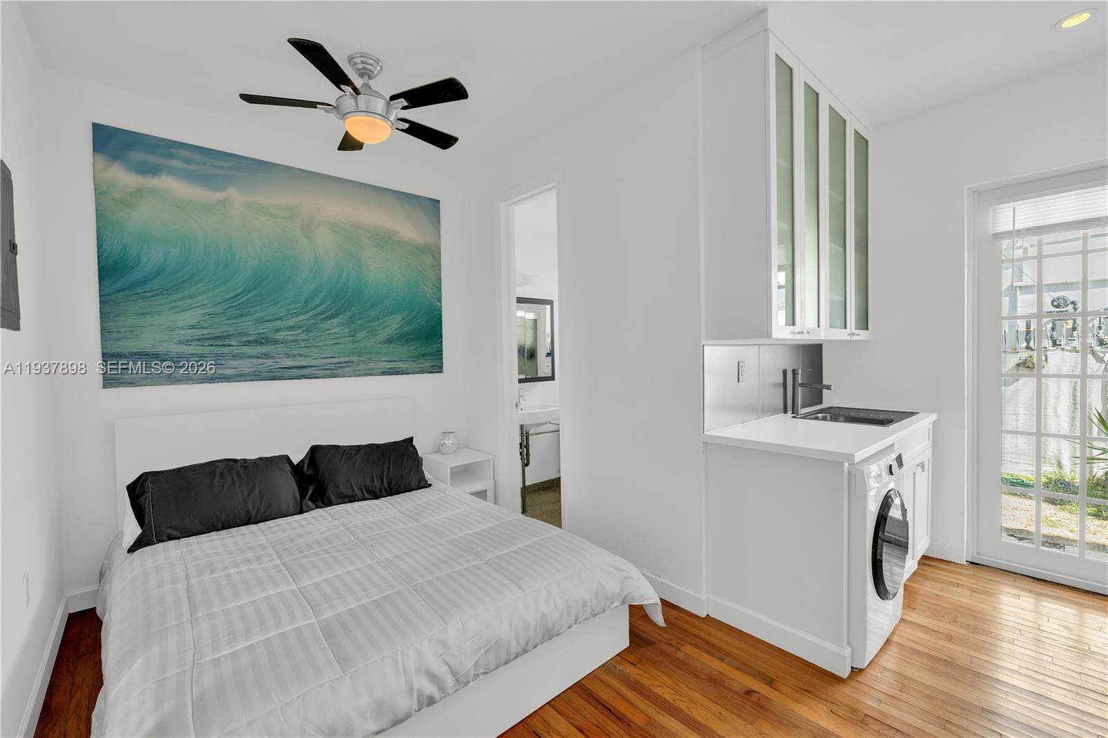 A bedroom features a bed, a wave wall art piece, and a small kitchenette area — 439 15th St # 2, Miami Beach FL 33139, MIAMI BEACH, FL