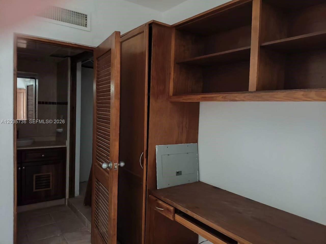 A room features a wooden desk, built-in shelving, a louvered closet door, and an adjacent bathroom — 1 Punta cana # 0, FL, FL