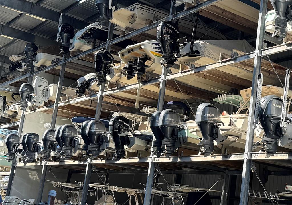 Multiple boats are stored on a multi-level metal rack system inside a large warehouse — 100 CIRCUIT ROAD UNIT N-52, NOKOMIS, FL