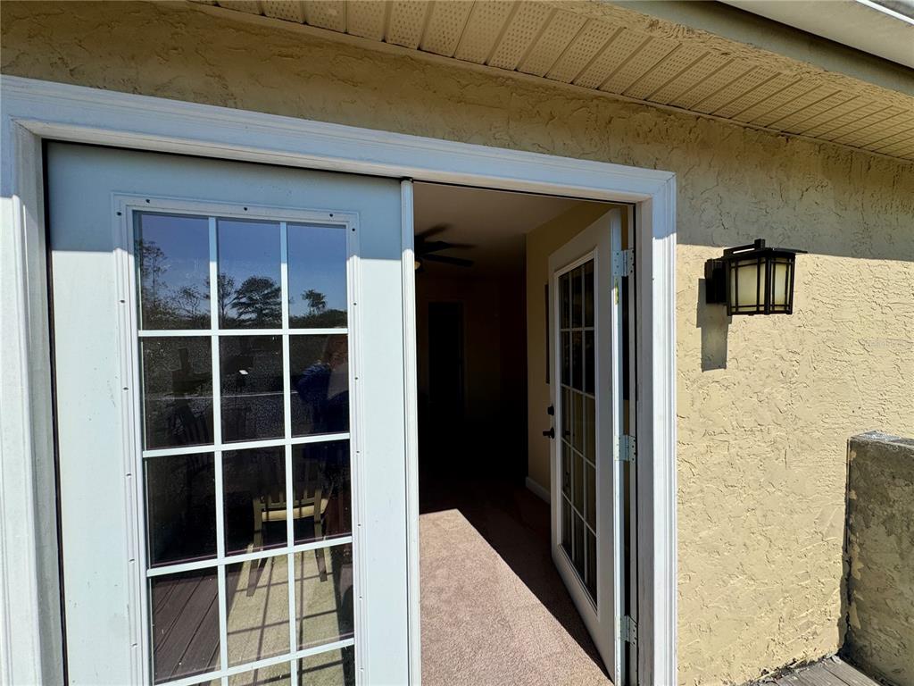 A pair of white French doors opens from a stucco exterior into a carpeted room — 862 CYPRESS LAKES BOULEVARD UNIT 1, TARPON SPRINGS, FL