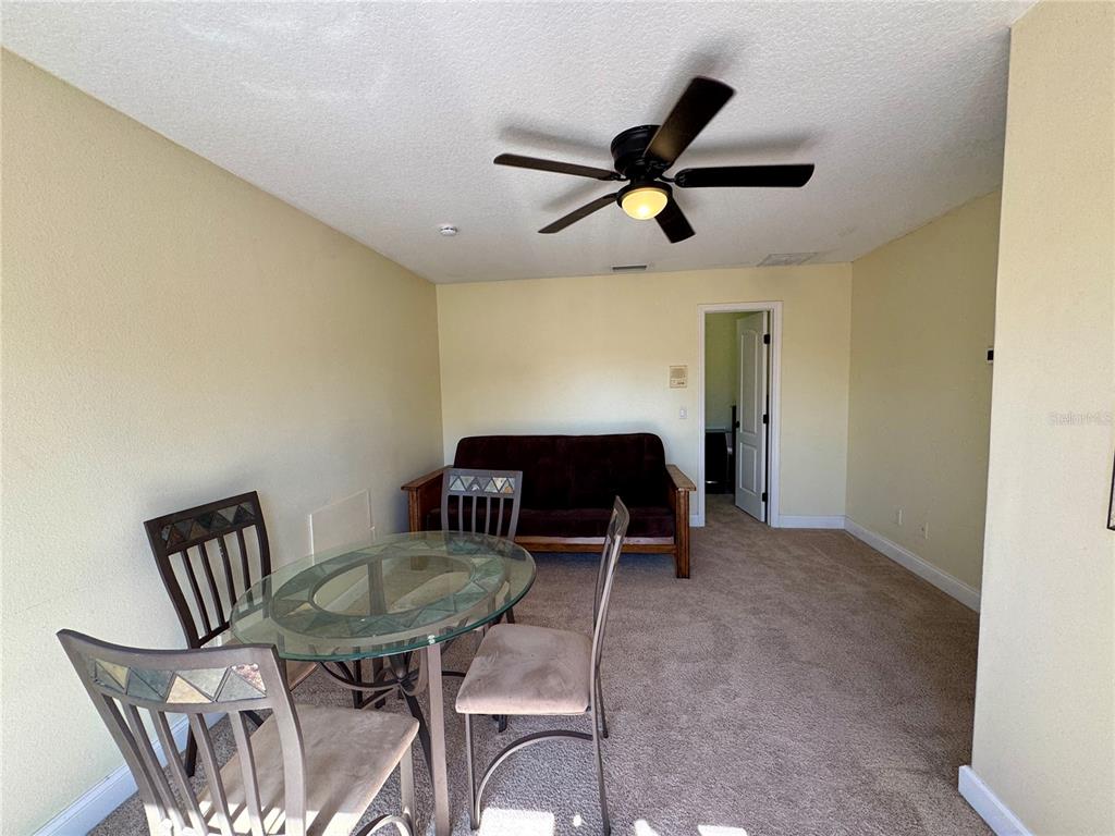 A room features a glass dining table, four chairs, a futon, and a ceiling fan — 862 CYPRESS LAKES BOULEVARD UNIT 1, TARPON SPRINGS, FL