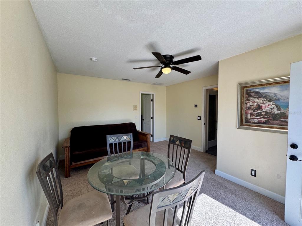 A dining area with a glass table, four chairs, and a futon on carpeted flooring — 862 CYPRESS LAKES BOULEVARD UNIT 1, TARPON SPRINGS, FL