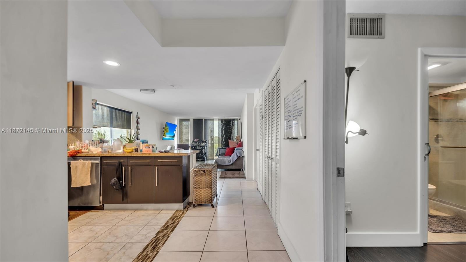 A kitchen with dark cabinets and a tiled floor opens into a living area — 8001 Crespi Blvd # 4B, Miami Beach FL 33141, MIAMI BEACH, FL