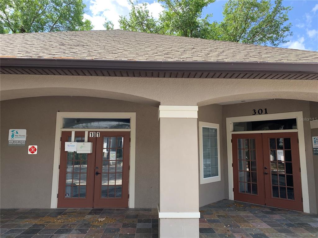 The exterior of a commercial building features two glass-paned double doors labeled 101 and 301 — 25 WINDSORMERE WAY, OVIEDO, FL