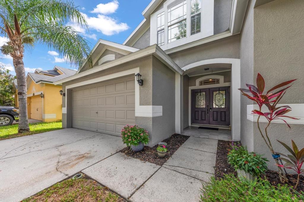 A gray two-story house features a double-car garage, a covered entryway, and a palm tree — 4422 HAVELOCKE DRIVE, LAND O LAKES, FL