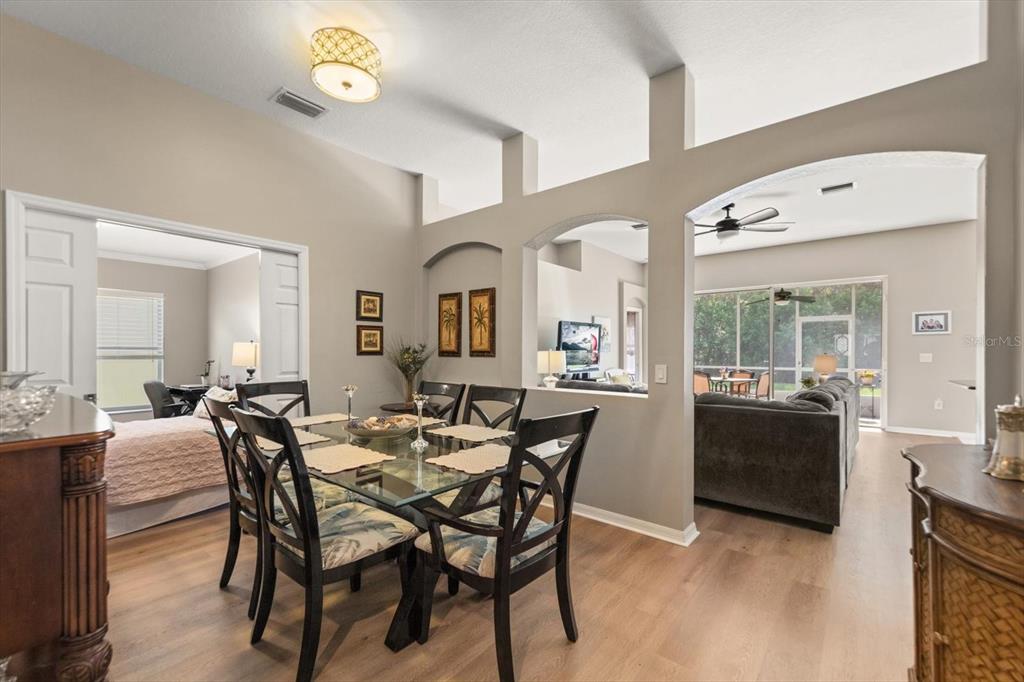 A dining area with a glass table and chairs opens into a living room — 4422 HAVELOCKE DRIVE, LAND O LAKES, FL