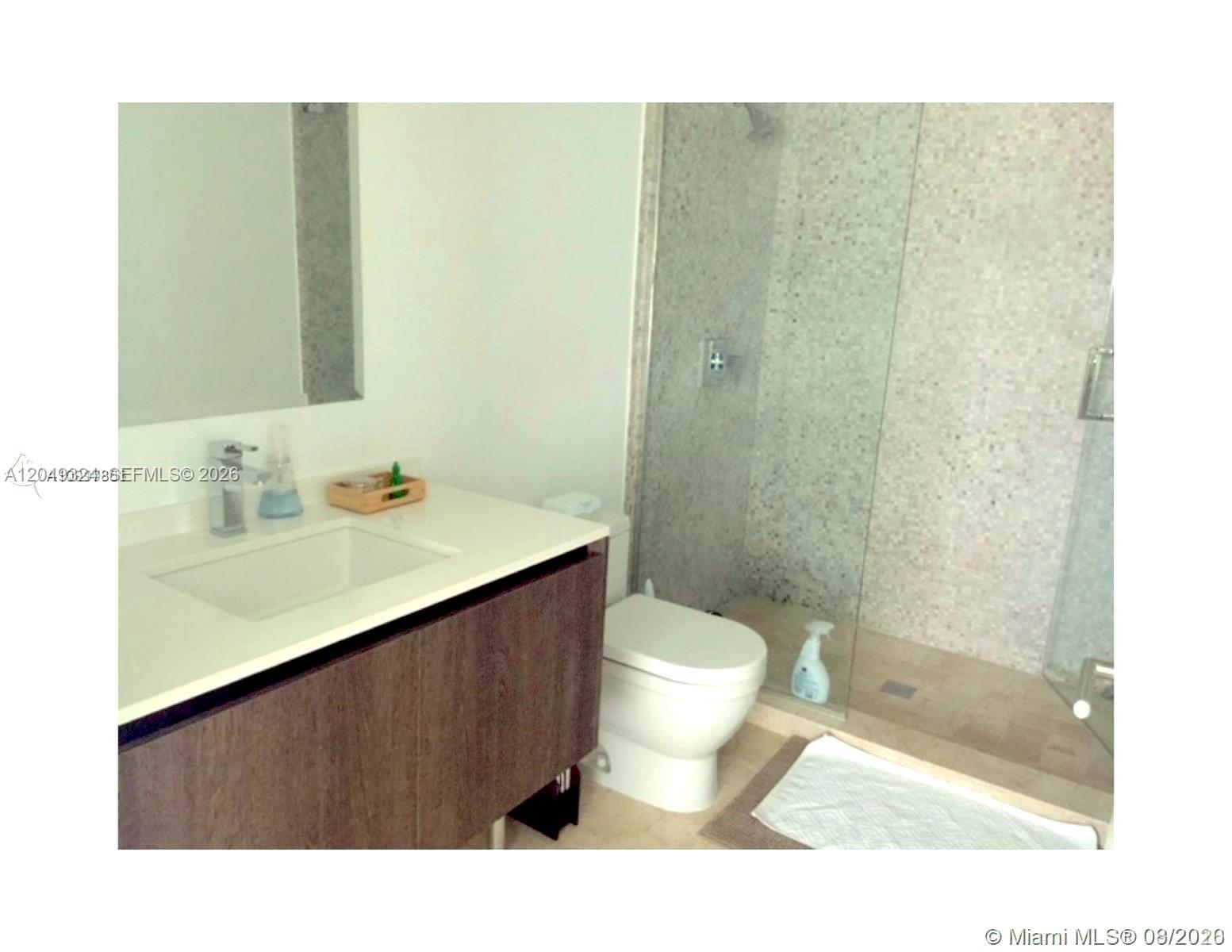 A bathroom features a vanity with a white countertop, a toilet, and a glass-enclosed shower — 68 SE 6th St # 2007, Miami FL 33131, MIAMI, FL