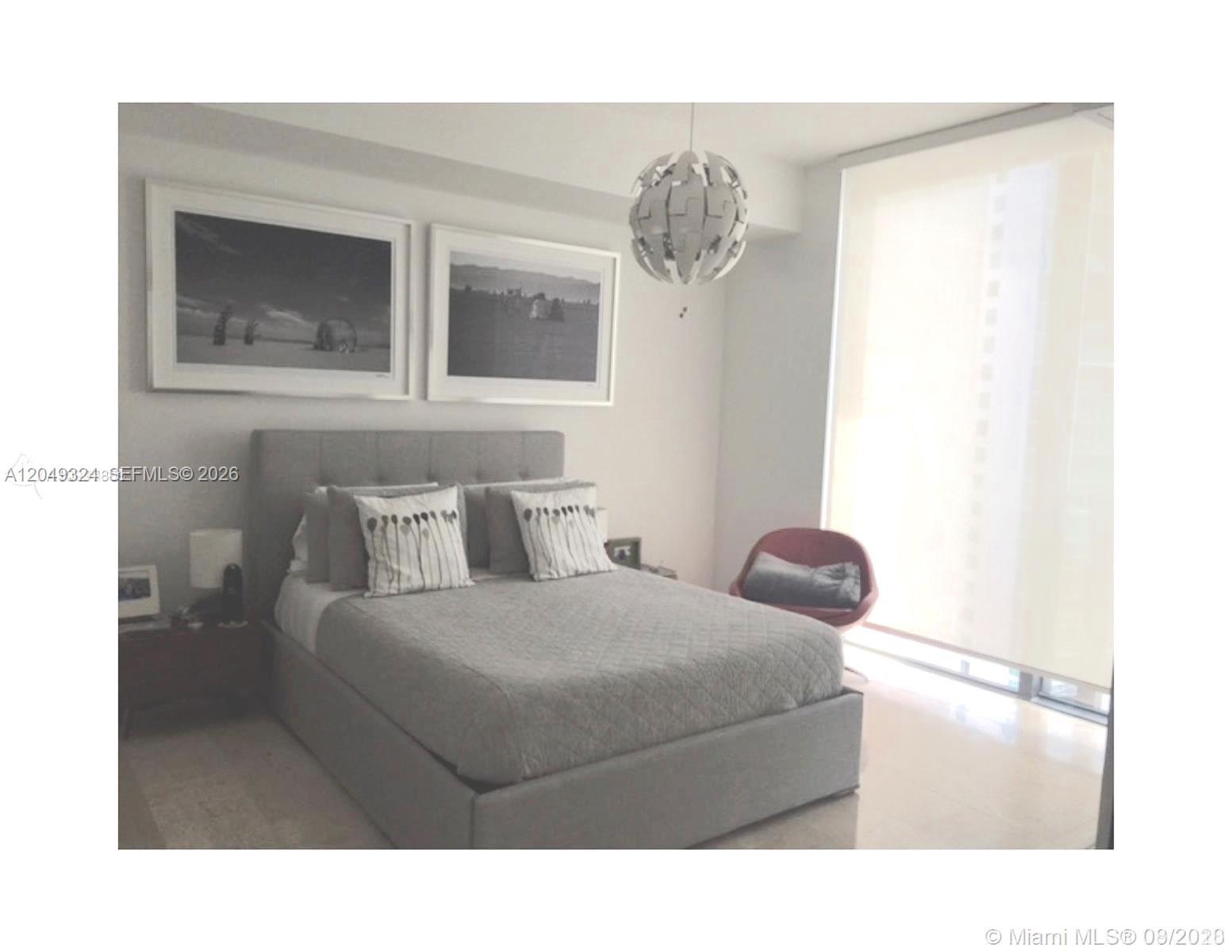 A bedroom features a gray upholstered bed, two framed landscape prints, and a modern pendant light — 68 SE 6th St # 2007, Miami FL 33131, MIAMI, FL
